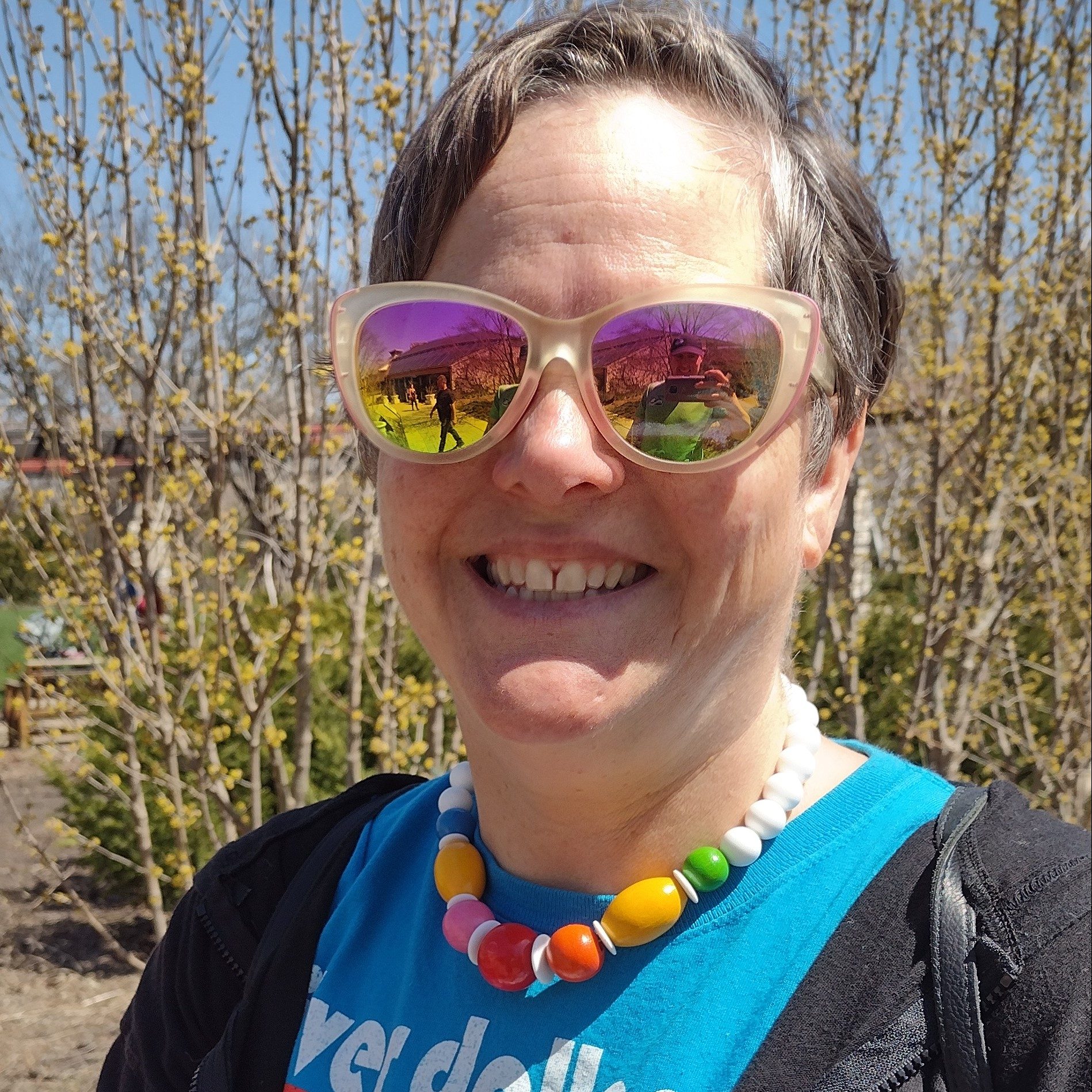 photo of lisa outside wearing sunglasses with a rainbow colored necklace on